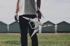 A person holding a white quadcopter drone in an outdoor setting, illustrating trends in technology in the future of gadgets.